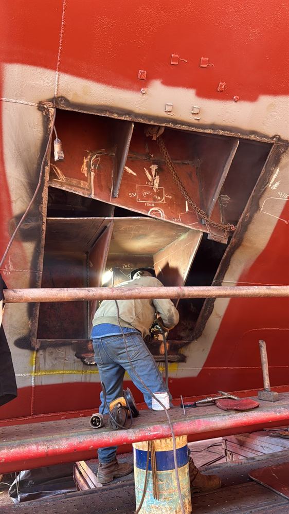 Soldador trabajando dentro de una abertura practicada en el casco